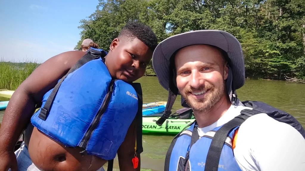 Brian smiles next to a young boy wearing a blue life vest