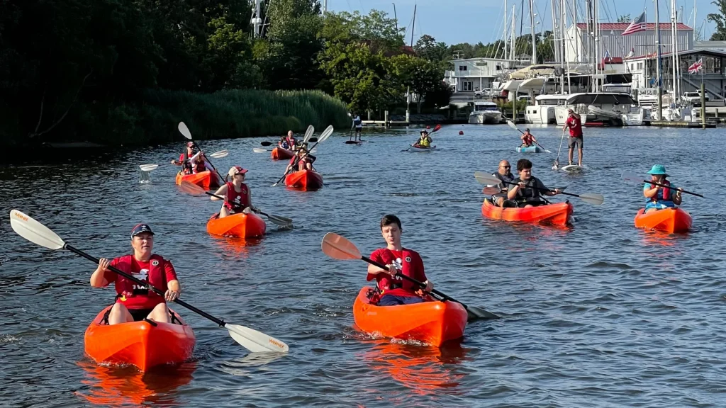 Several paddlers in orange kayaks