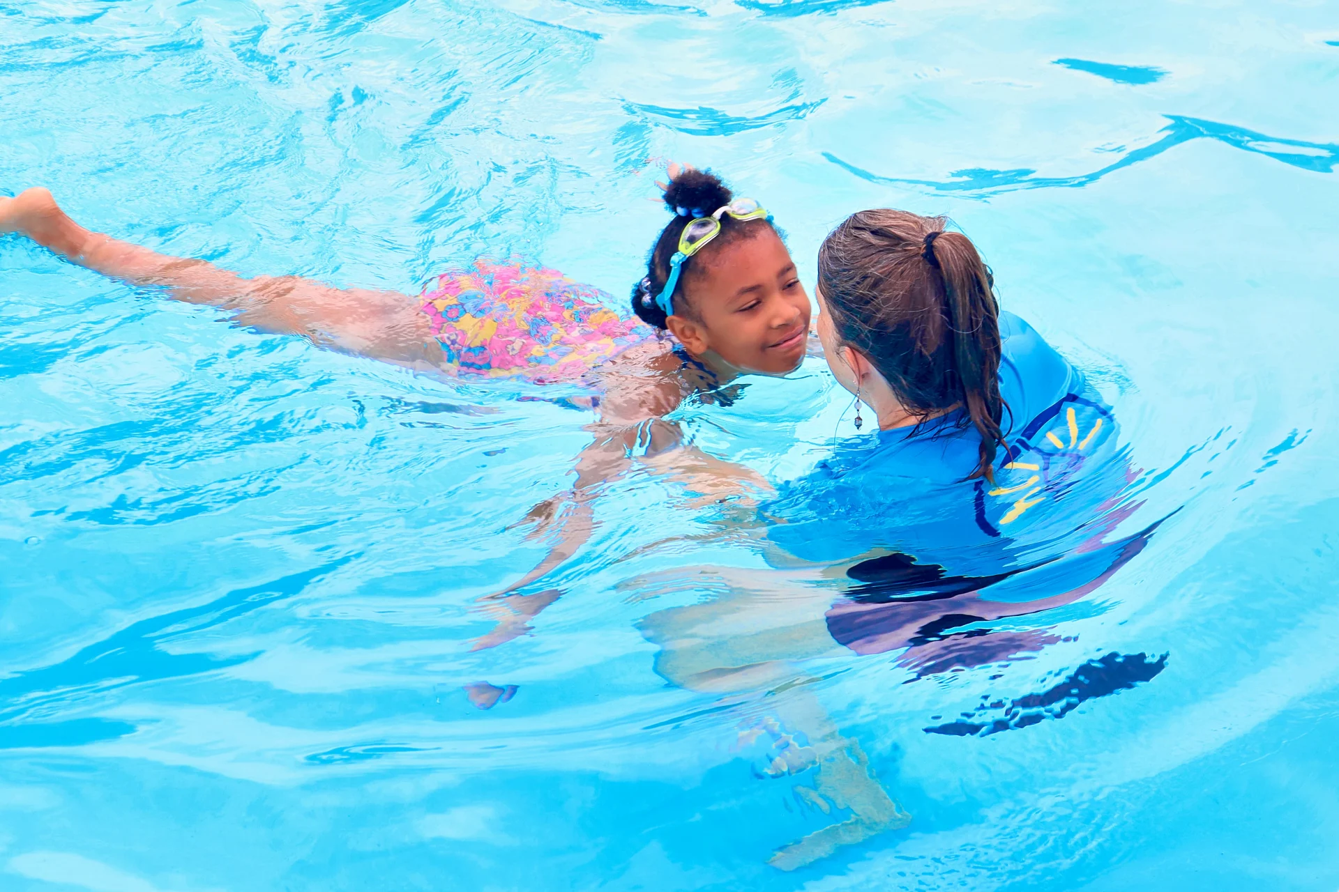 child swims up a woman in a pool