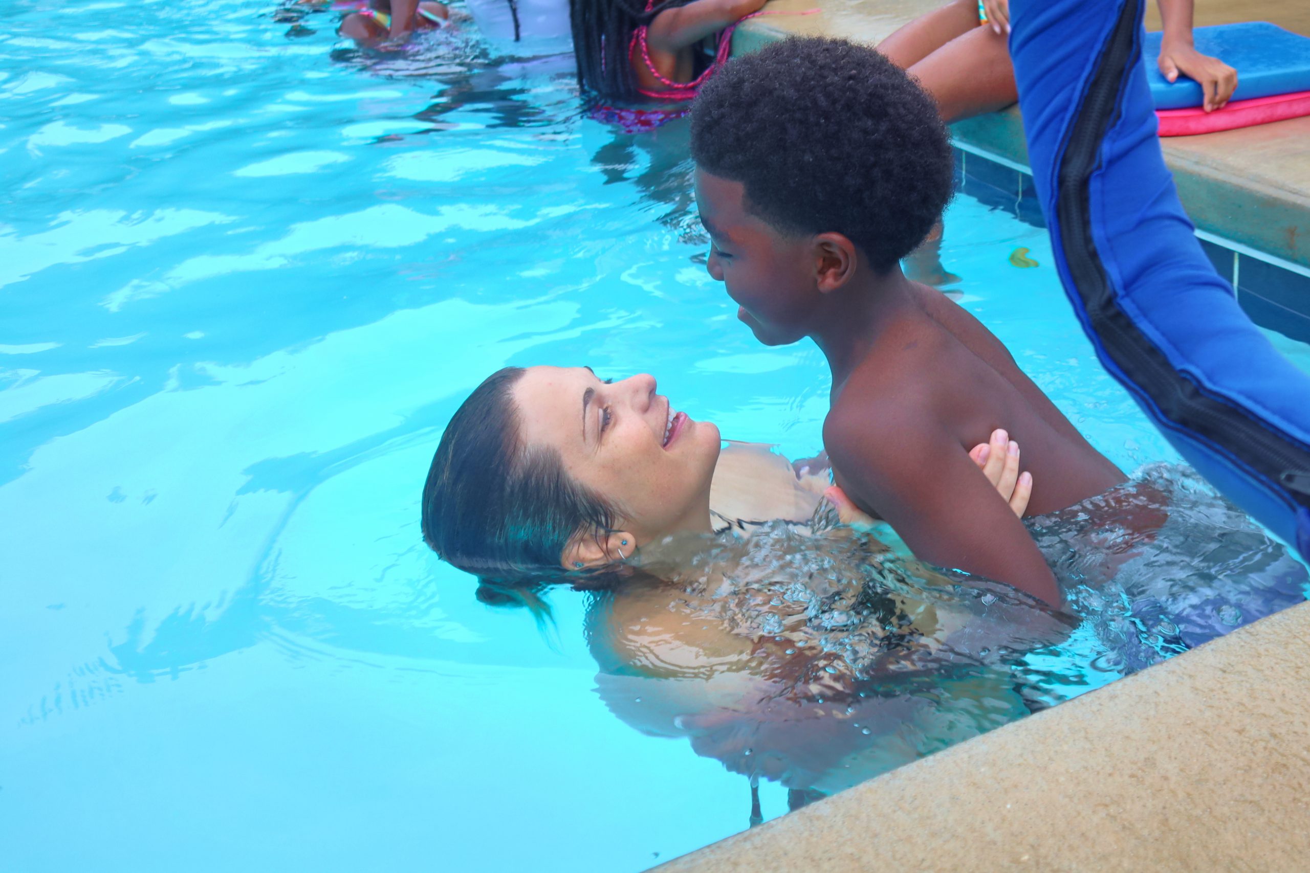 Woman holding child up in pool