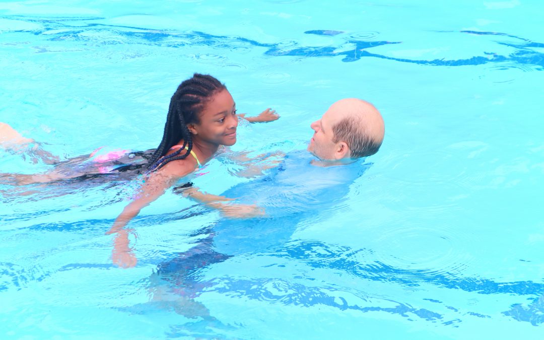 Man receiving a girl learning to swim in a pool