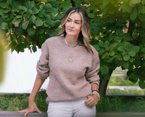 Jennifer standing in front of a tree wearing a soft brown sweater