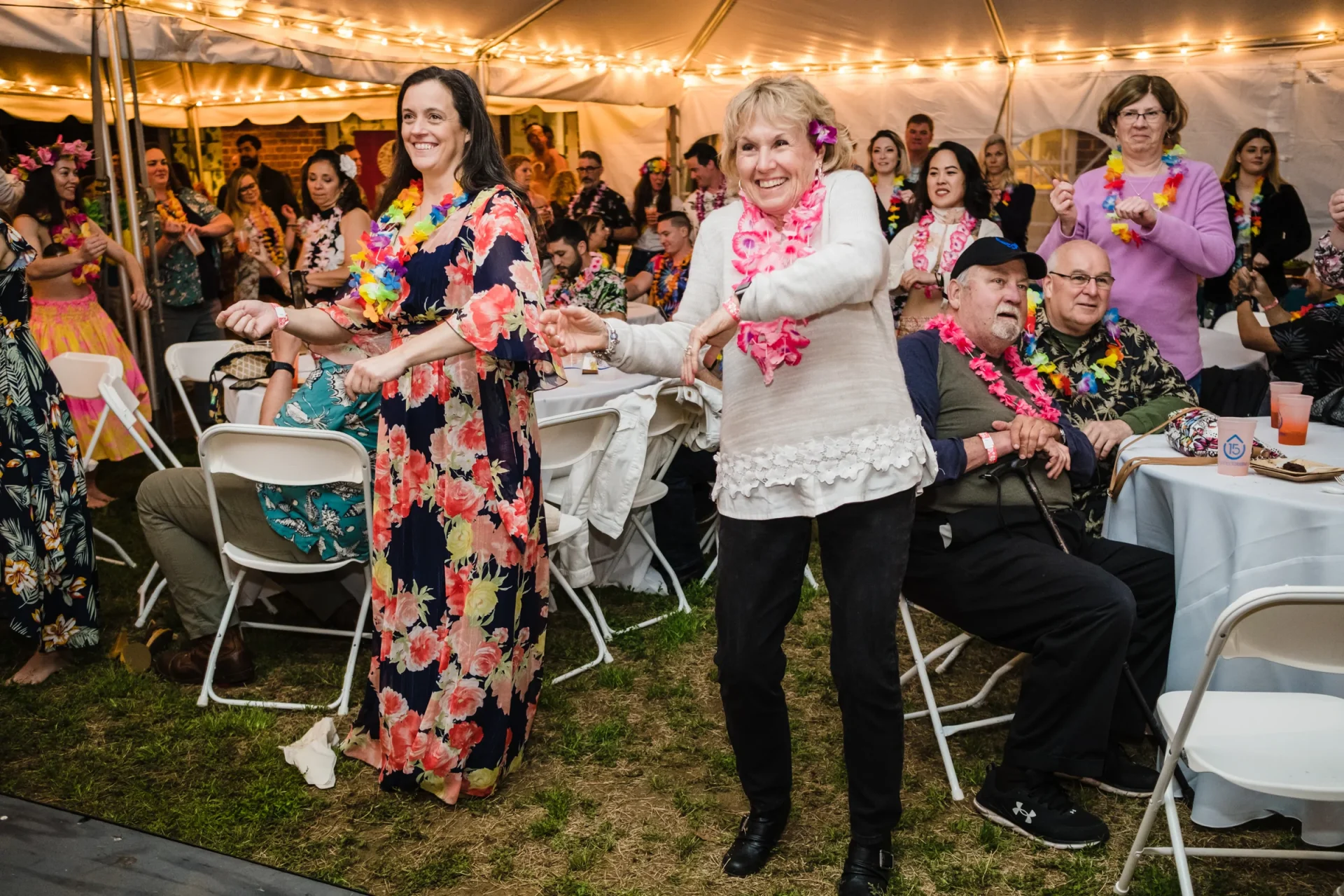 Two women dancing hula in an event crowd