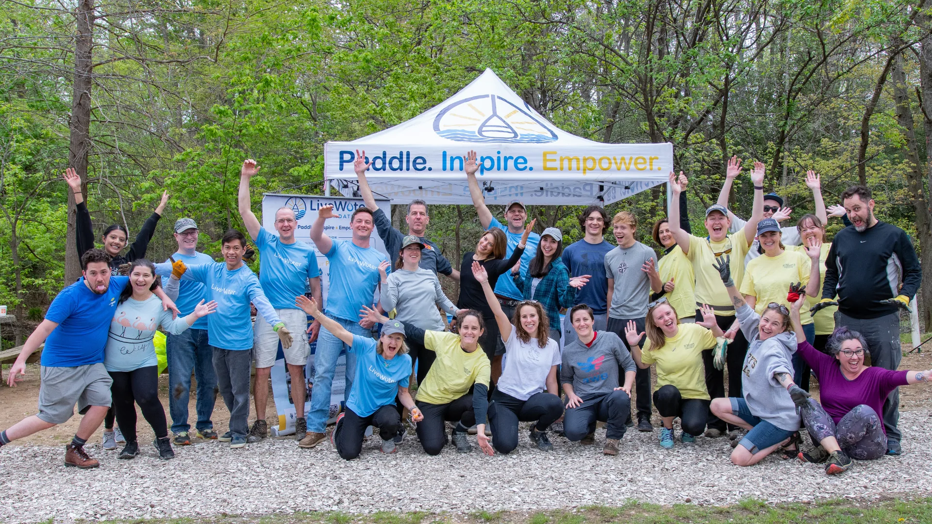 group in front of a canopy with Paddle Inspire Empower and the LWF logo