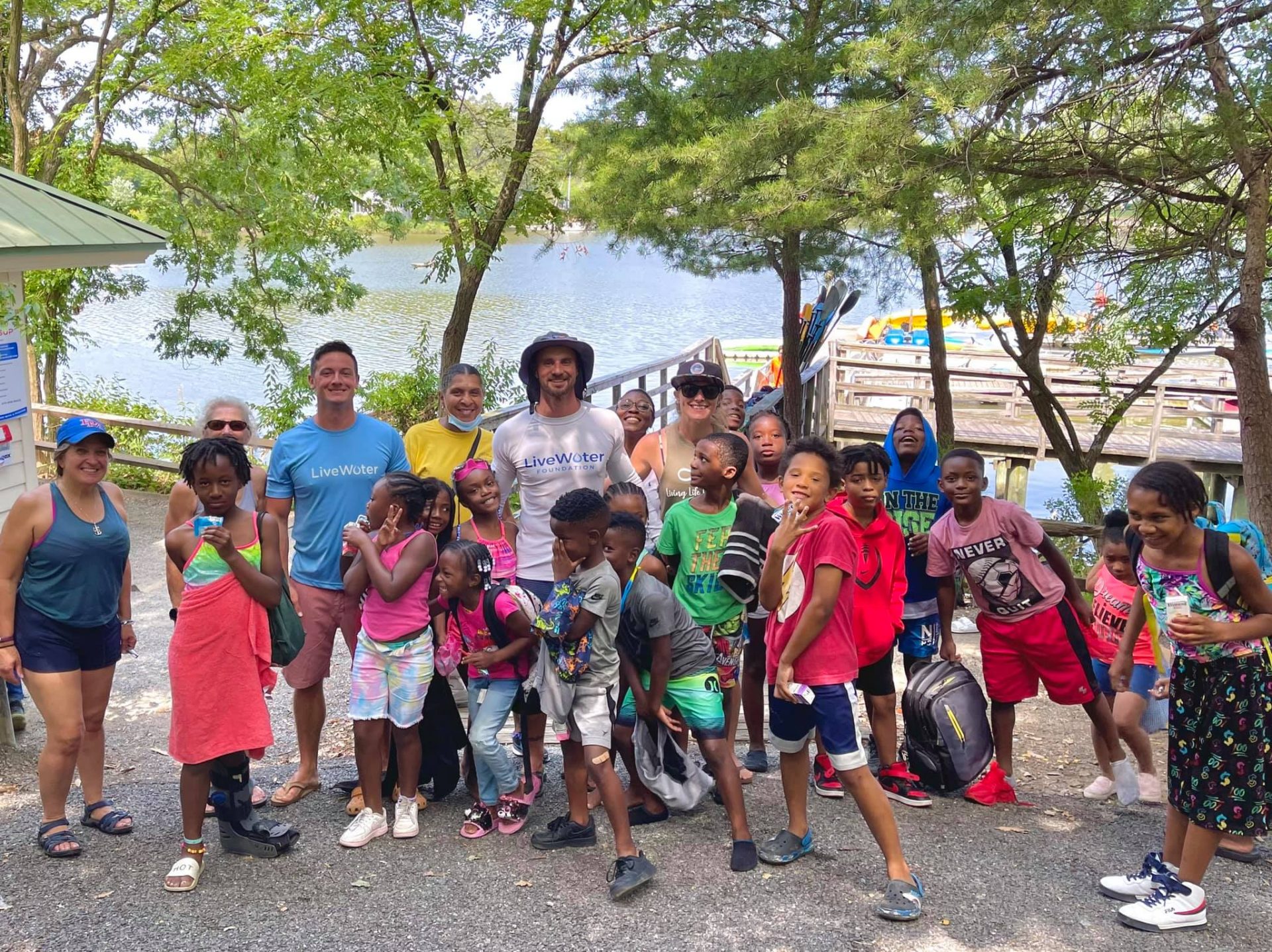 Several Live Water Foundation members stand with a group of children