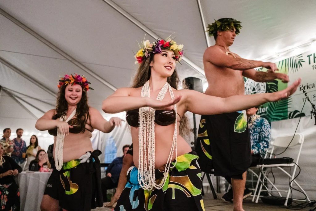 Two women and a man dancing hula