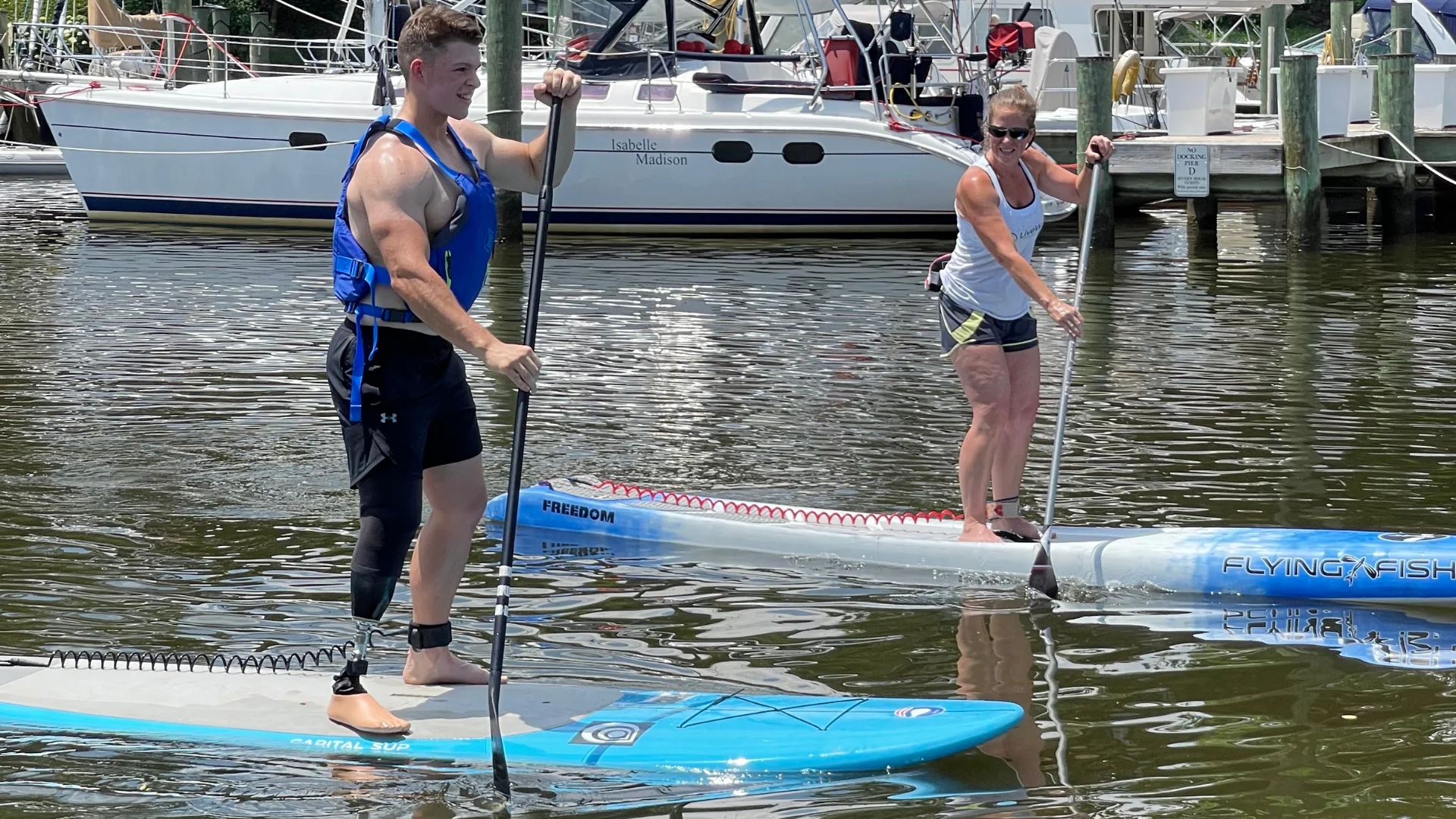 A man with an augmented leg paddles alongside an instructor